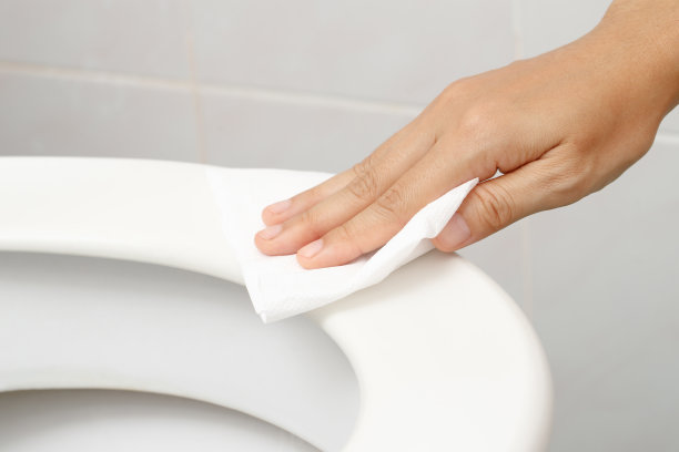 妇女用纸巾在家里的浴室里清洁马桶。图片下载