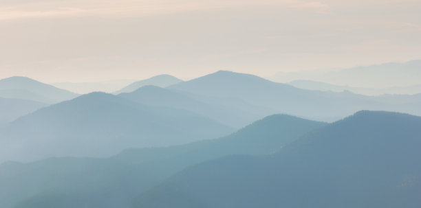 温暖的黎明天空的梯度之上的山和岩石的剪影。黑色的落基山脉和橙色的日出天空生动的高山景观。极简的高原风景与落基山脉的剪影图片下载
