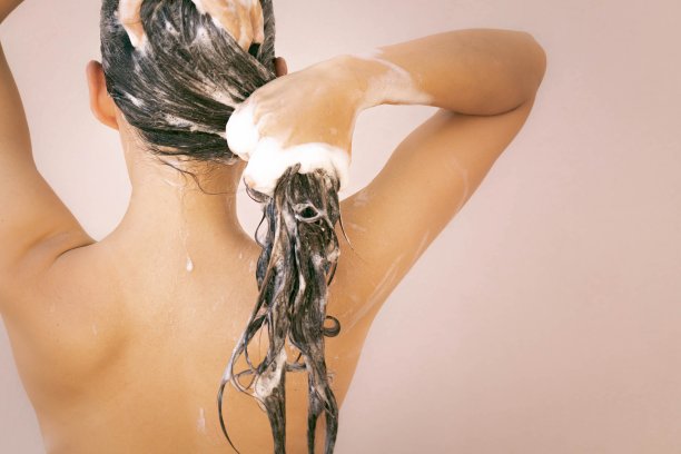 一个美丽的女人正在洗澡，用香波和水洗头。身体和头发护理。图片下载