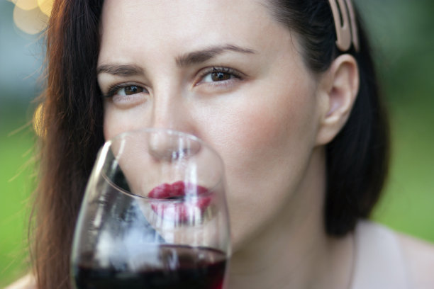 一幅深色头发的女人用酒杯喝红酒的特写画像图片下载