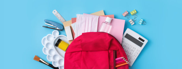 粉红色背包与文具在蓝色的桌子背景。图片下载
