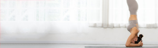 亚洲妇女身穿运动服在窗前做瑜伽练习的横幅，瑜伽手倒立或平cha Mayurasana，健康年轻妇女在家中平静的呼吸和冥想瑜伽图片下载