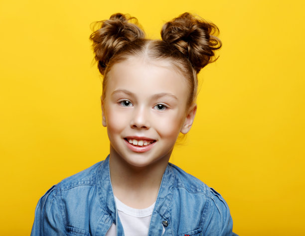 黄色背景上欢快微笑的小女孩的肖像图片下载