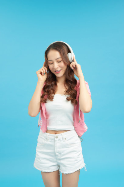 女人听音乐和娱乐-隔离在一个蓝色的背景图片下载