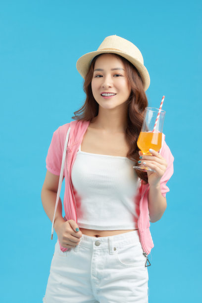 在蓝色背景下喝着苏打水的漂亮女人的形象。图片下载