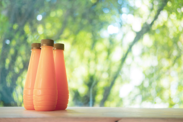 木桌上一组装在塑料瓶里的橙汁。图片下载