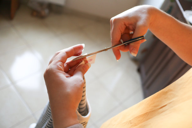 一名女子用剪刀从新衣服上剪下标签图片下载