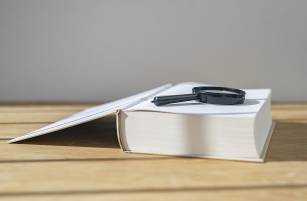 放大镜与打开厚书木制书桌与日光图片下载