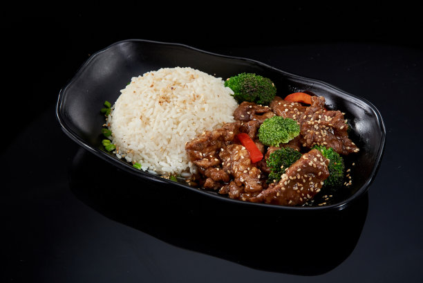 在黑色背景的黑色盘子上蒸米饭和牛肉酱图片下载