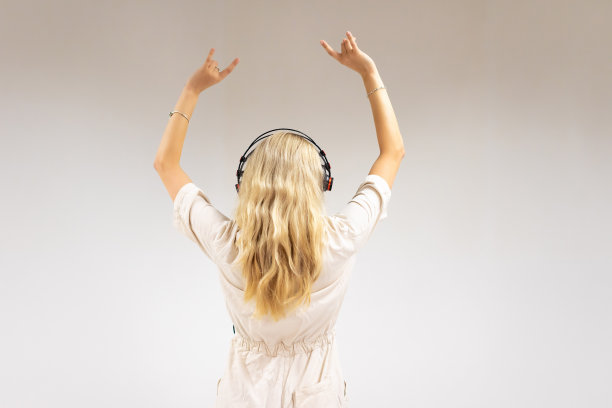 美丽的年轻金发女子在白色背景下听音乐图片下载