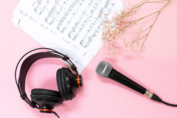 俯视图的平铺的音乐笔记，麦克风和耳机和鲜花在粉红色的背景图片下载