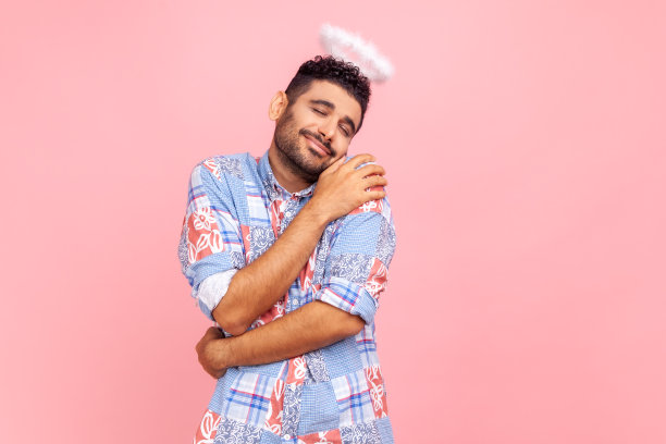 令人惊叹的天使般男子面带光环，面带微笑，拥抱自己，自我喜爱和支持图片下载