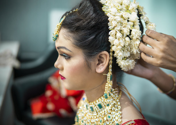 美丽的传统印度新娘正在美容师为她的婚礼做准备。图片下载