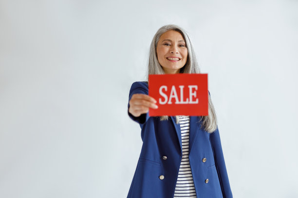 美丽的亚洲女人与松散的灰色头发显示红色卡片与文字销售在光的背景图片下载