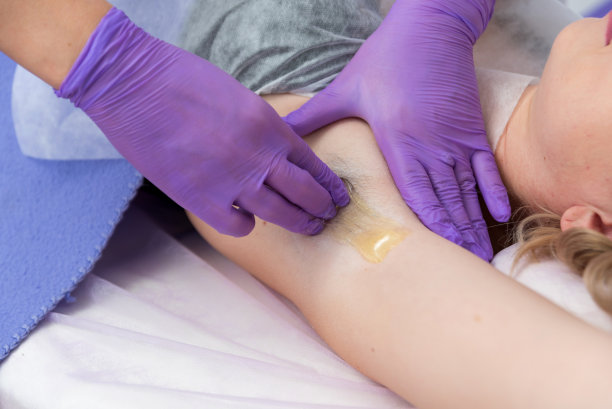 糖脱毛概念。在水疗沙龙用糖糊处理腋下女孩脱毛，白色背景。图片下载