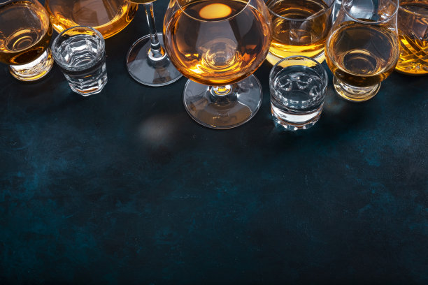 烈性酒、烈性酒、烈性酒和蒸馏酒放在玻璃杯里:干邑白兰地、苏格兰威士忌和其他。蓝色背景，俯视图图片下载