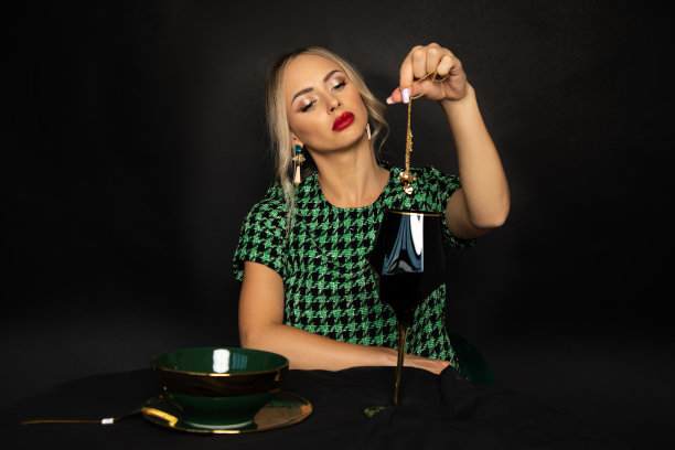 美丽的年轻女巫与红色口红在她的嘴唇和化妆召唤在黑色的背景，魔法仪式的财富。工作室的照片图片下载