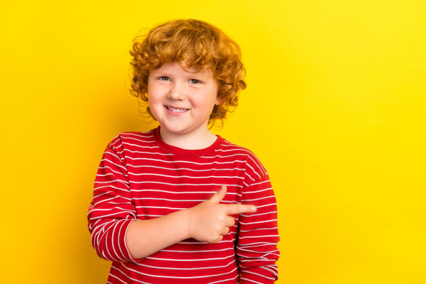 照片中古怪的小男孩点了空，穿着红色的衬衫孤立在黄色的背景上图片下载