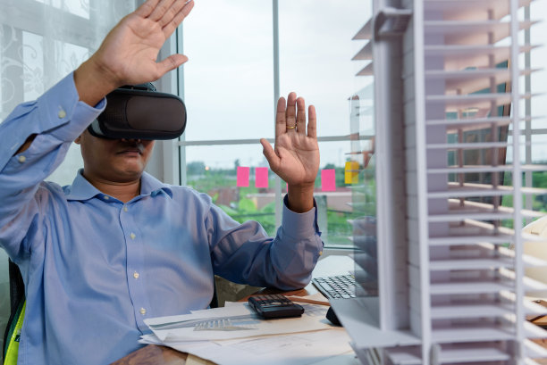 工程师或建筑师佩带虚拟现实头戴式工作与虚拟现实建模软件应用程序。运用虚拟现实建模和BIM技术在建筑中完成。图片下载