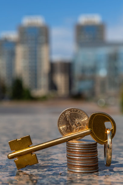 现代建筑背景上的金钥匙和美国钱币柱图片下载