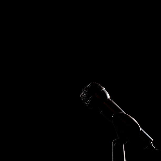 黑色背景下的黑色麦克风。黑色miccrophone图标。舞台上有麦克风和复制空间。图片下载