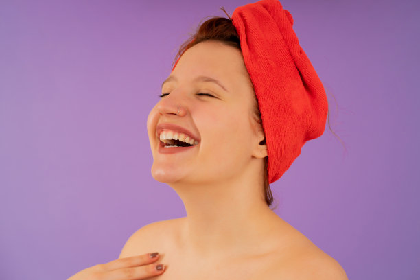 年轻女子头戴毛巾面带微笑。图片下载