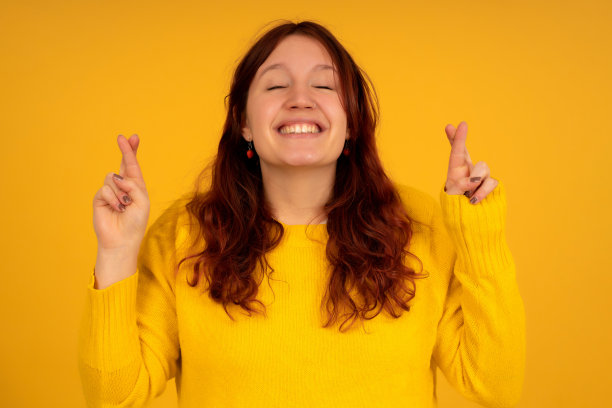 年轻女子交叉手指，祝好运。图片下载