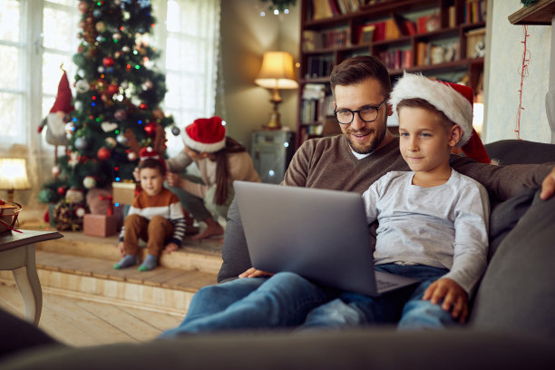 圣诞节当天，父亲和儿子在家里放松时使用笔记本电脑。图片下载