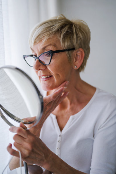 一位老妇人在家里照镜子做皮肤护理图片下载