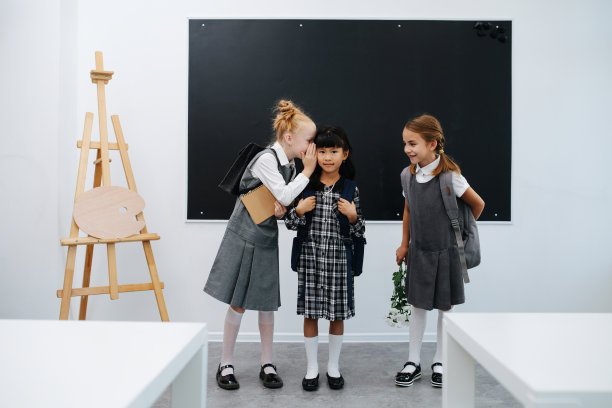 背着书包站在黑板前闲聊的女学生。图片下载