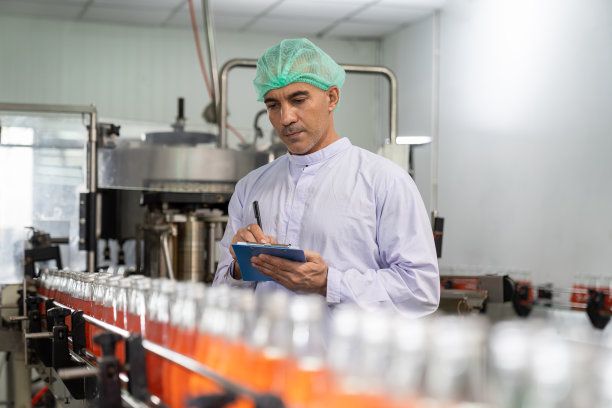 饮料厂男工人在传送带上写罗勒籽和水果的产品笔记。专业人员检查灌装生产线的加工情况。检验质量控制图片下载