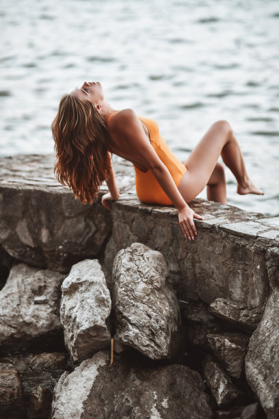 女性坐在湖边的石头码头和放松在日落图片下载