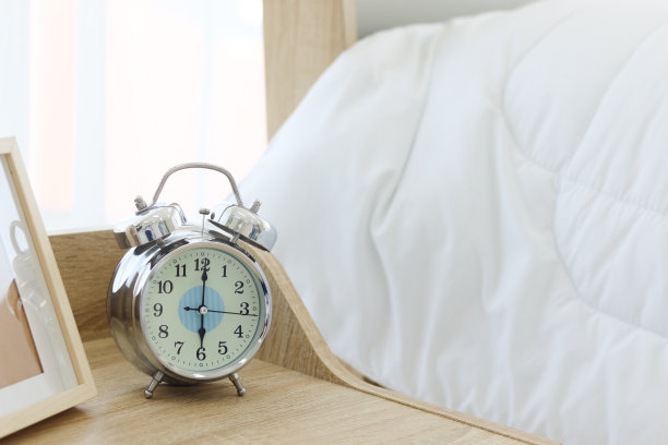 早上六点，白色卧室的木桌上放着闹钟。图片下载