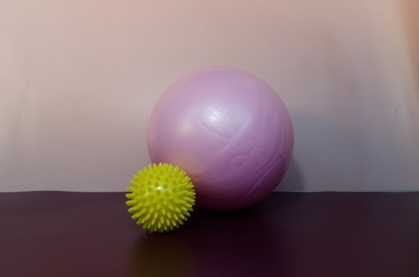 粉红色的运动橡皮球和紫色背景上有针的黄色按摩球图片下载