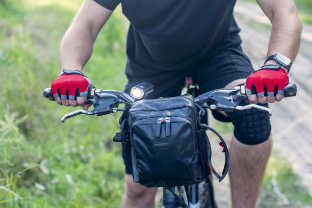 戴着手套骑山地车的人，车把上有包。图片下载