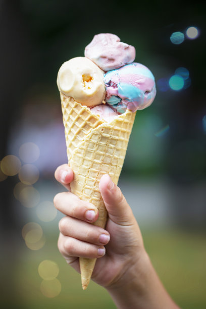 手握冰淇淋蛋筒，背景色彩缤纷。图片下载
