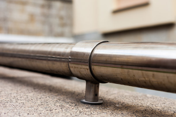 闪亮的金属管固定在城市中心的石头支架上图片下载