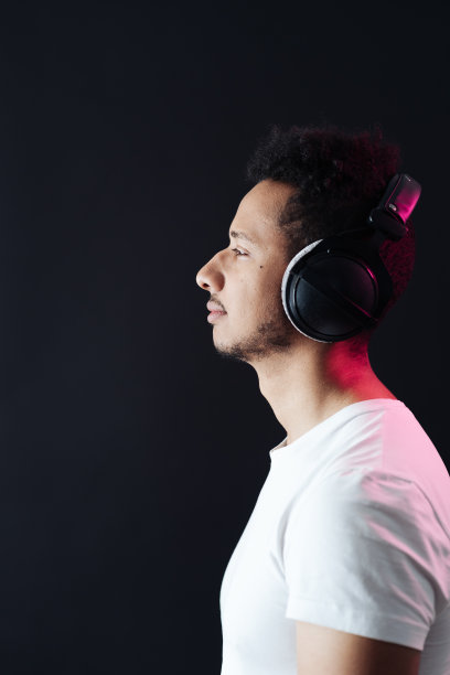 无忧无虑的深色皮肤的家伙肖像戴着耳机在黑色背景图片下载