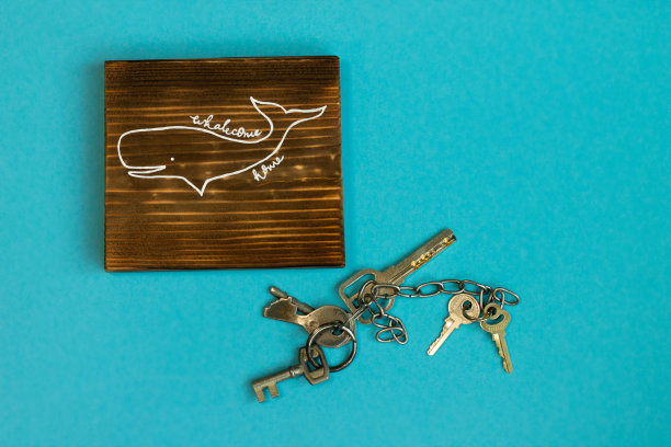 烧焦的木头手工制作的标志鲸鱼回家与蓝色背景上的鲸鱼和钥匙。欢迎回家。呆在家里。图片下载