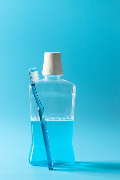 漱口瓶和蓝色背景上的蓝色牙刷，是口腔卫生概念必不可少的东西。图片下载