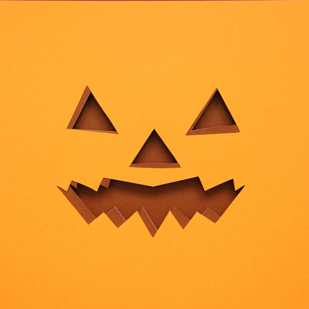 万圣节背景概念用纸艺术作品吓人的万圣节南瓜脸，两层橙色的纸和棕色的纸剪成杰克灯的脸的形状。图片下载