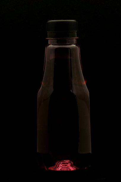 塑料瓶子装满了食用色素，在黑色背景上有灯光效果图片下载