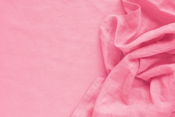 漂亮的粉红色皱巴巴的餐巾在台布的背景上。图片下载