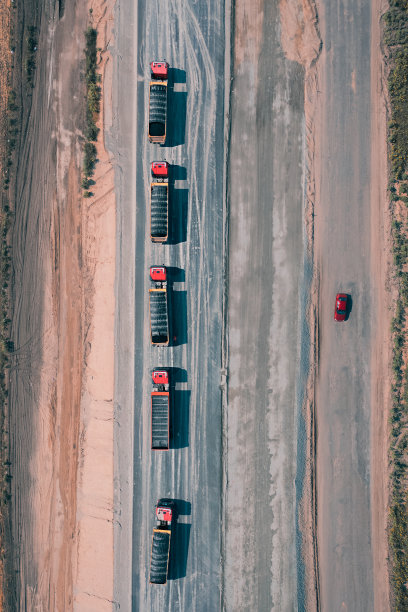 卡车车队行驶在柏油路上，一辆红色汽车在另一边的道路上，俯视图图片下载