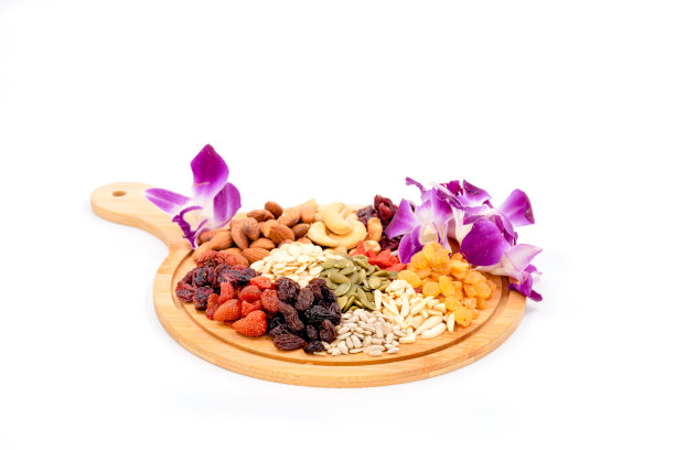 一组各种各样的干果和干粮与美丽的兰花放在木盘上。图片下载