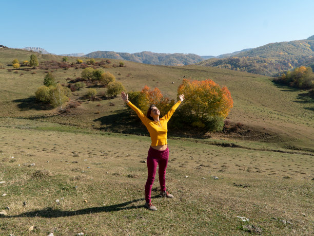‌在高加索山脉的秋天，快乐的妇女举起双臂享受阳光图片下载