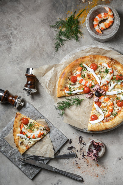 美味的披萨与金枪鱼，海鲜，虾和迷你章鱼大理石圆形托盘。在灰色石头的背景上装饰着披萨配料图片下载