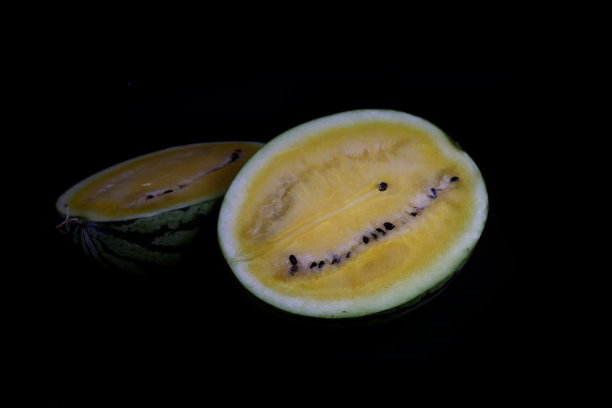 在黑色背景上切黄色西瓜图片下载