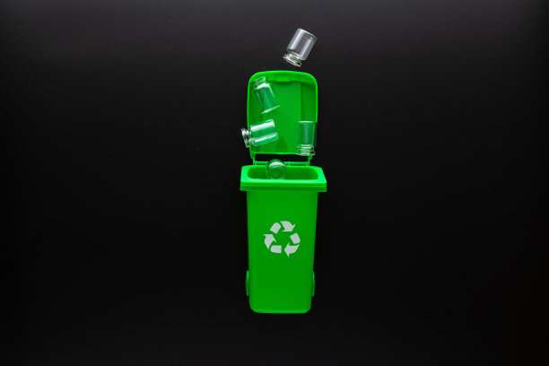 玻璃回收垃圾。黑色背景上的绿色玻璃回收垃圾桶。垃圾箱容器用于处理垃圾废物，节约环境。副本的空间。图片下载