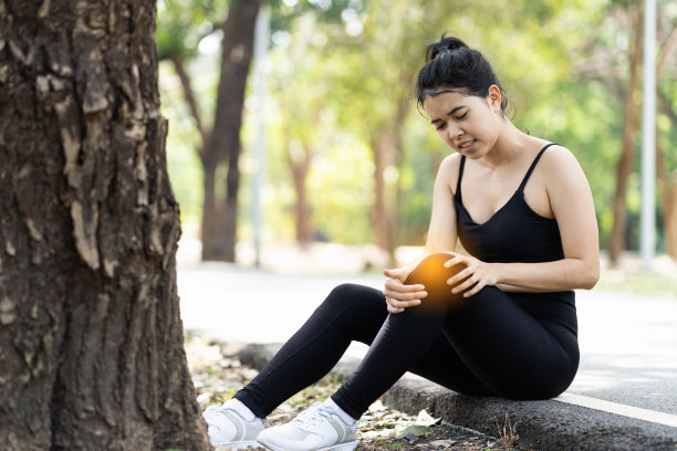 亚洲跑步运动女子膝盖受伤。一个膝盖疼痛的女人在公园里。户外运动的问题。妇女、运动和保健概念图片下载